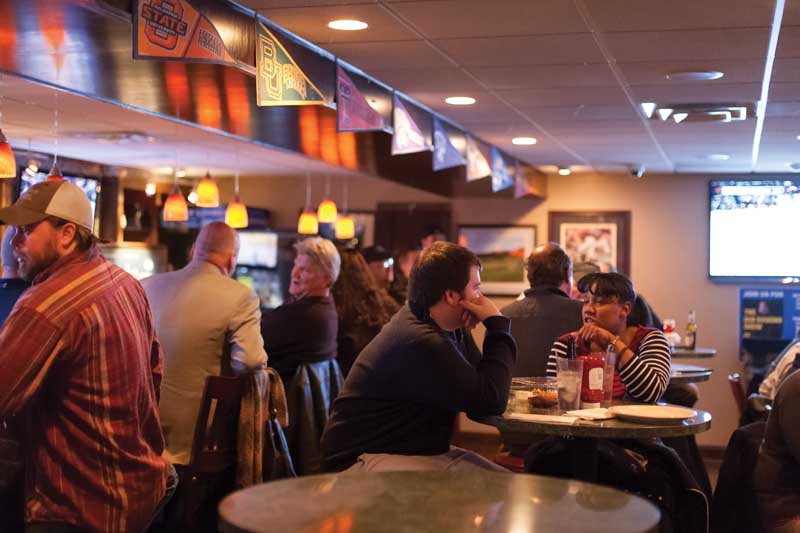 People in sports bar watching football on televisions