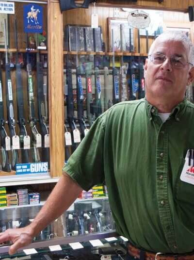 Man in front of gun counter in family owned store